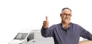 Volwassen man met een kartonnen doos die voor transportbusjes staat en een duim omhoog steekt, geïsoleerd op een witte achtergrond.